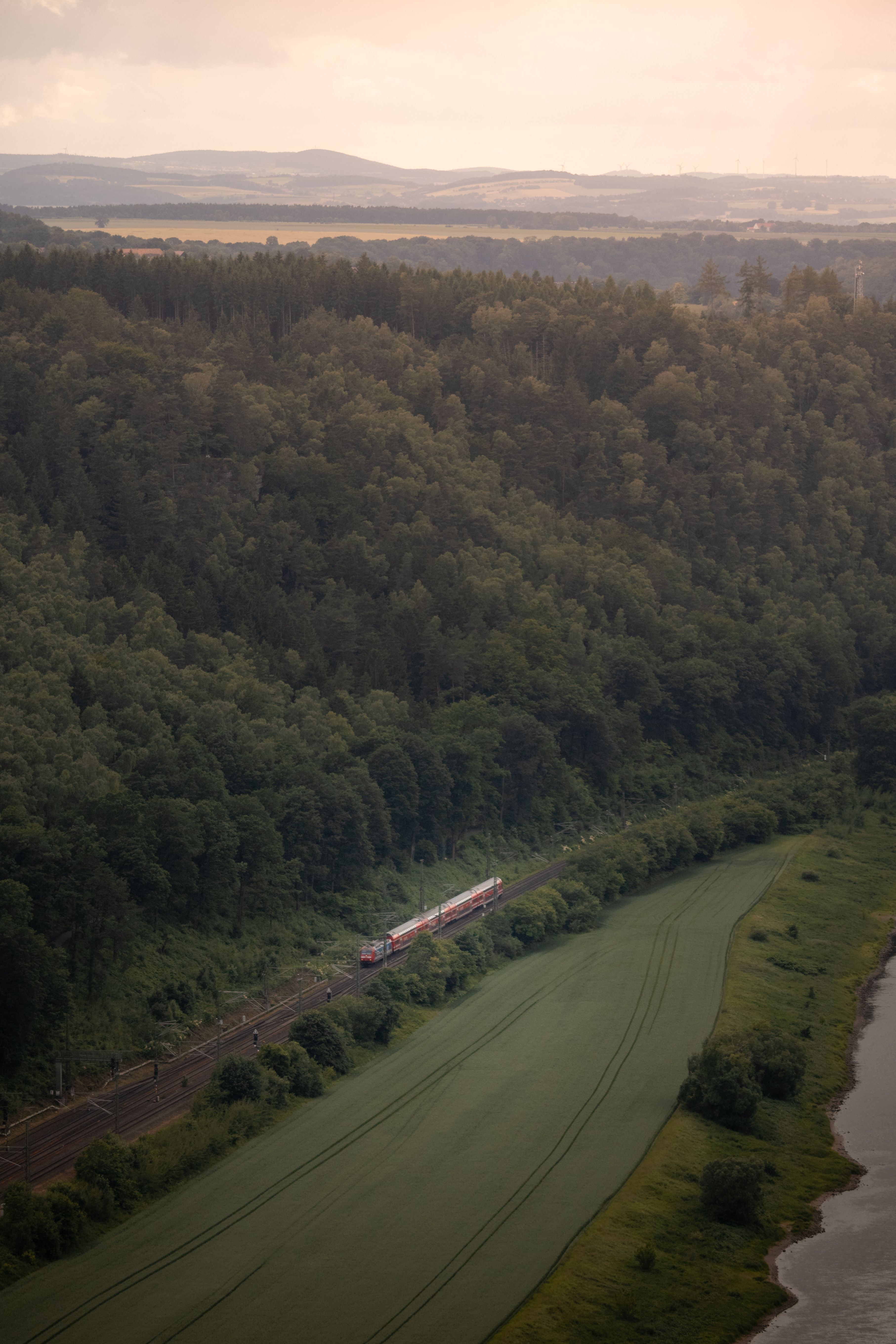 Aerial view of a train traveling through the verdant forests and fields of Saxony, Germany.